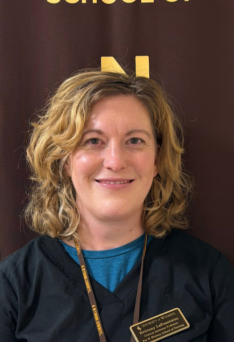 brittany lafountaine in her black scrubs standing in front of a brown nursing banner