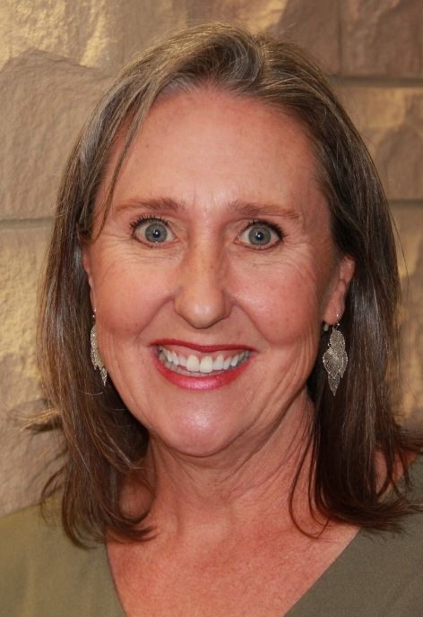 jennifer langevin in a green blouse standing in front of a lime stone wall