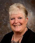 woman with frosted short hair, black dress, and large necklace