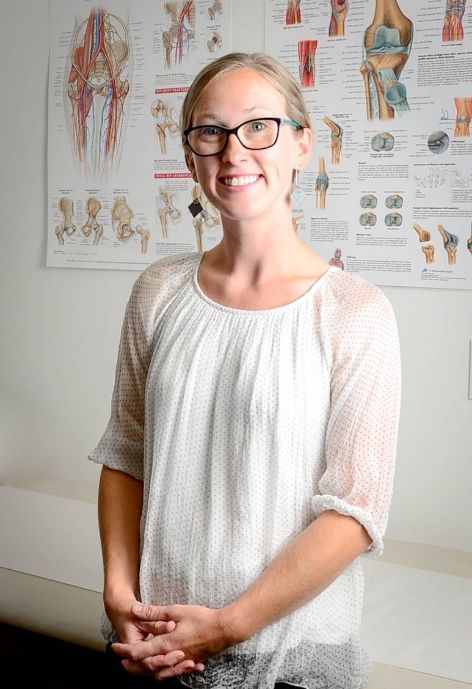 jesse morse-brady wearing white polka dot blouse standing in front of medical posters