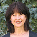 Woman with dark hair in front of fir tree