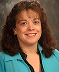woman with medium lenght reddish brown curly hair in a turquoise shirt