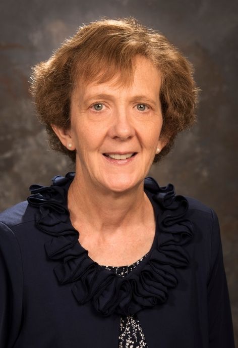 Sherrill Smith in Blue blouse in front of photo backdrop