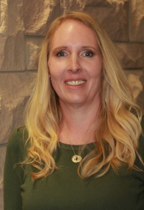 sarah whitman wearing a green shirt standing in front of a lime stone wall