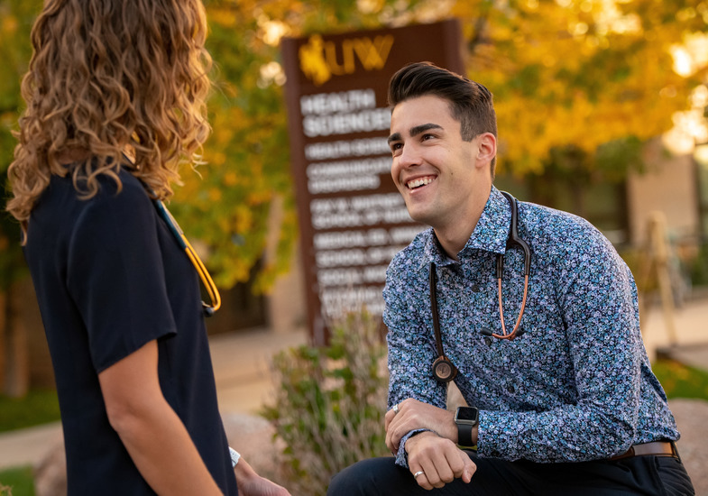 Two UW community members have a discussion outside the nursing school on the University of Wyoming campus.
