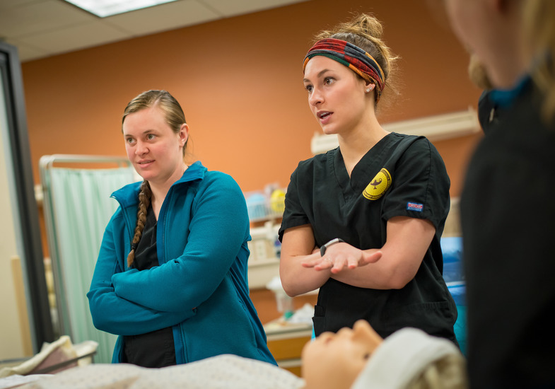 UW students in the nursing program discuss medical procedures over a simulator patient.