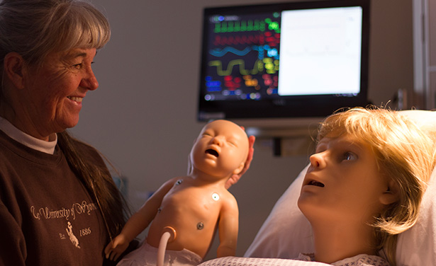 Woman holds simulated baby by simulated obstetrics model.