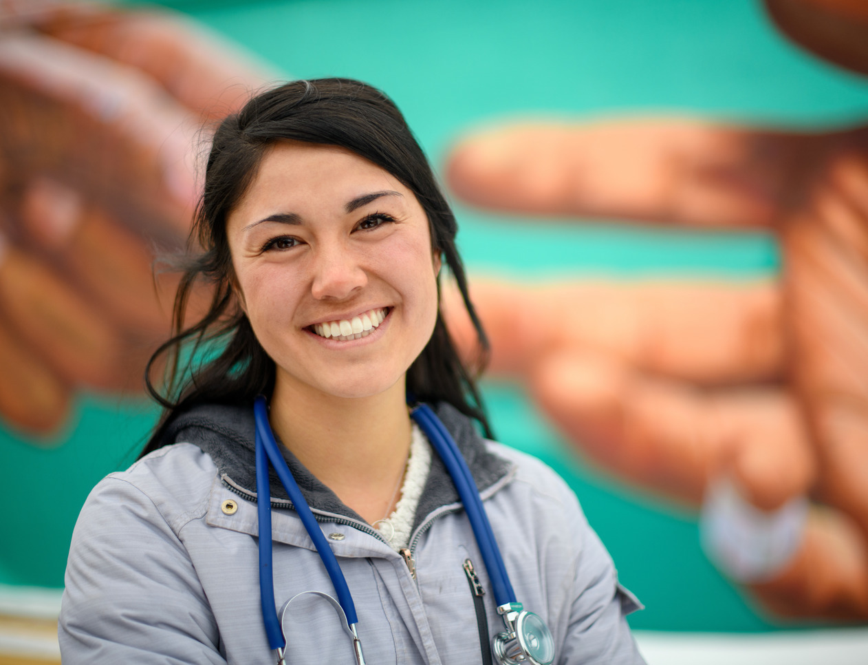 student stands in front of a mural