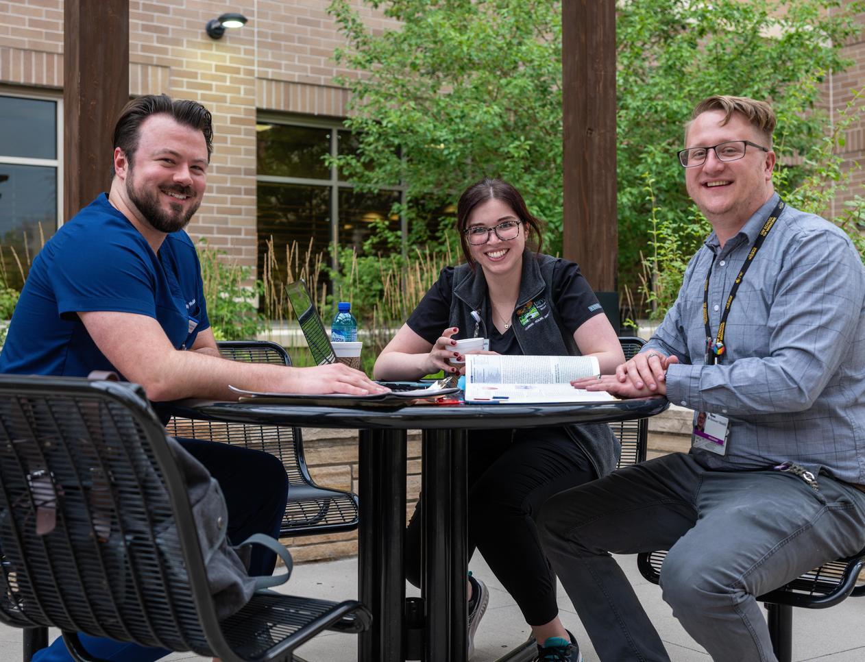 a group sits at an outdoor table with files and books open