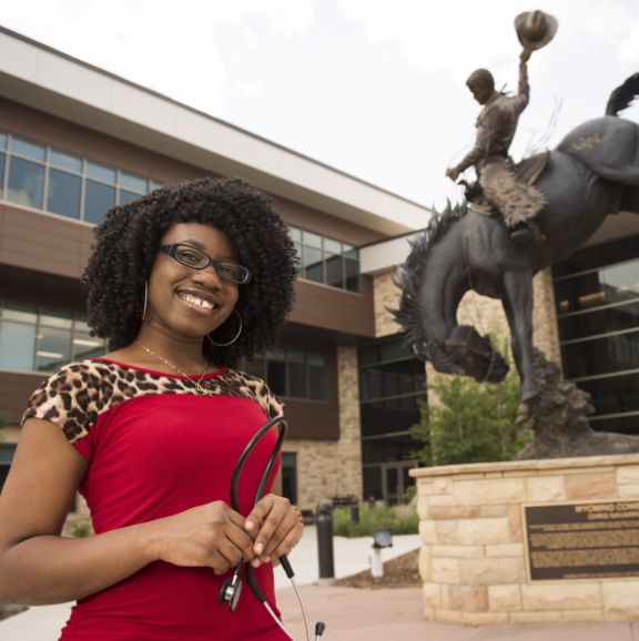 More Degree Information nurse in red shirt with stethescope standing in front of statue