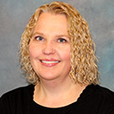 Woman with short blond curly hair, dressed in black