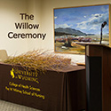 table with willow branches laying atop, podium, and lovely landscape picture on the wall