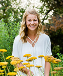 young woman with wavy blonde hair in white blouse in midst of lovely garden of yellow flowers