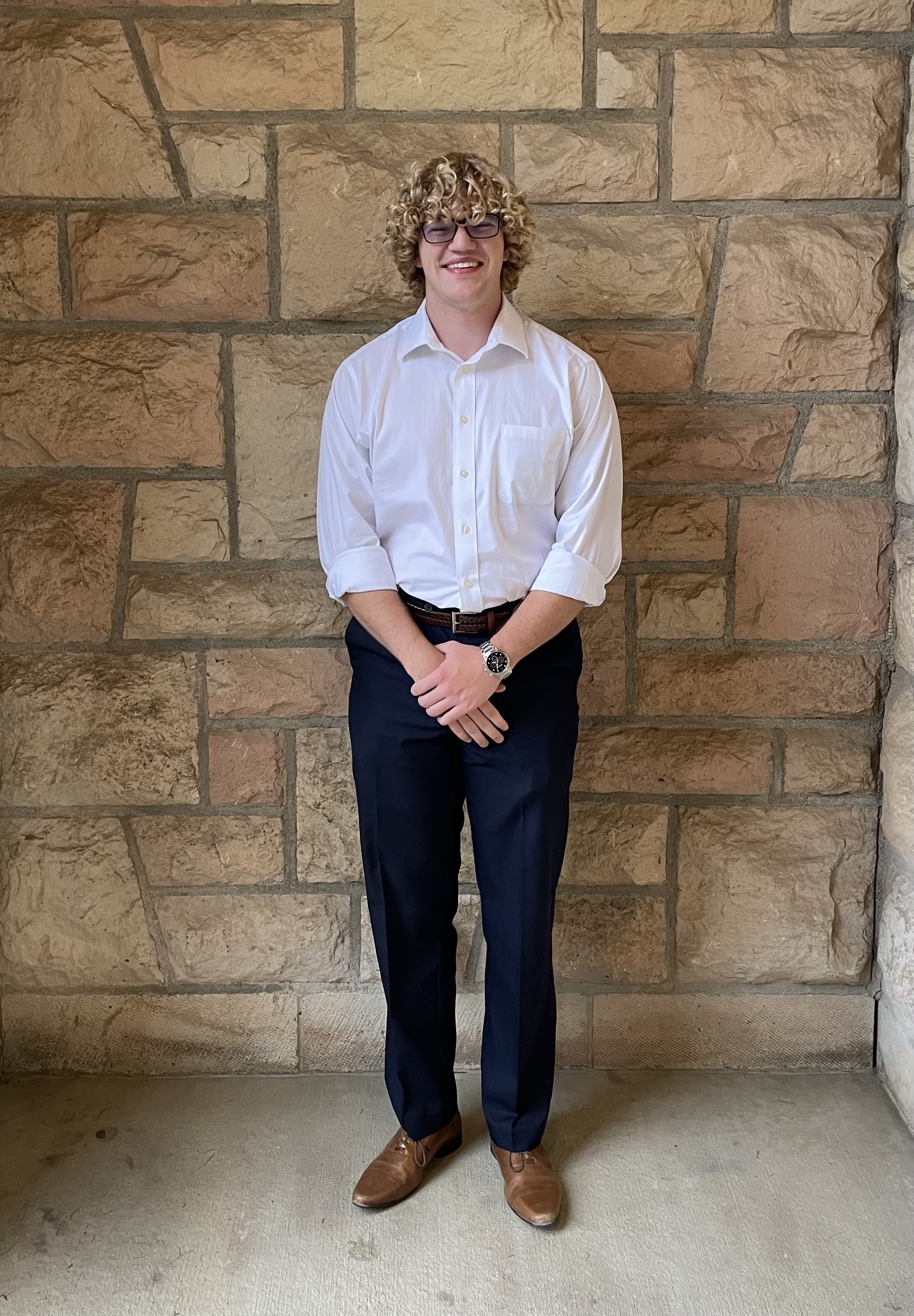 male student standing in front of brick wall