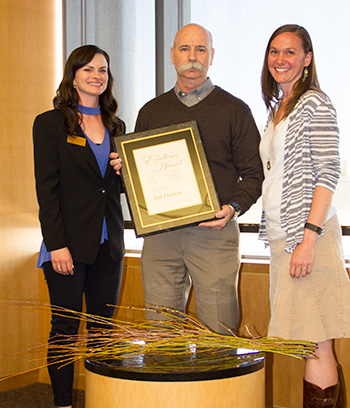 man holding award plaque flanked by a DNP student and a DNP faculty
