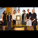 Seven individuals pose for picture with award plaque