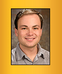 Young man with receding brown hair; grey shirt