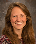 young woman with soft, full brown hair in striped sweater