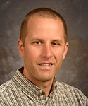 young man with hair buzzed, plaid green and white shirt