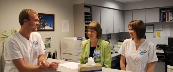 nurse manager and two students visit over hospital business office counter