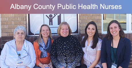 five women sit on bench outside brick building