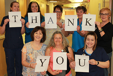 Eight employees holding up signs spelling THANK YOU