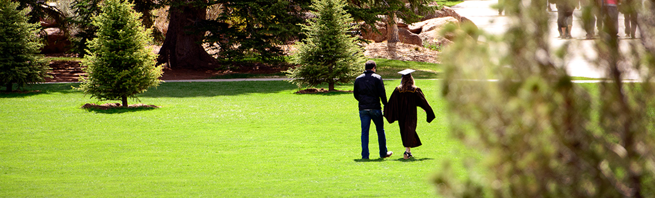 Students walking across campus in graduation garb in the spring