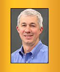 Man with short white hair an blue collared shirt