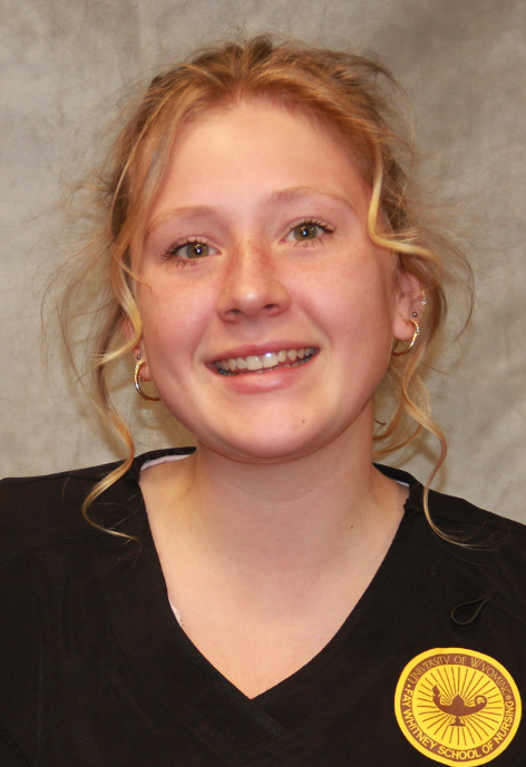 photo of Elli in black scrubs with a yellow patch