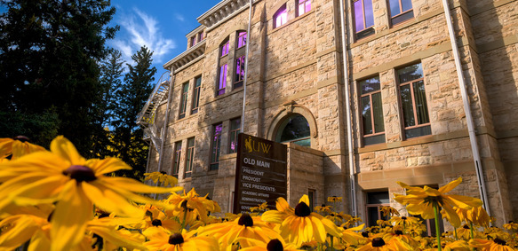 Image of Old Main with yellow flowers in the foreground
