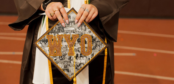 Image of  UW graduate's cap decorated with UWYO and pictures of friends and family