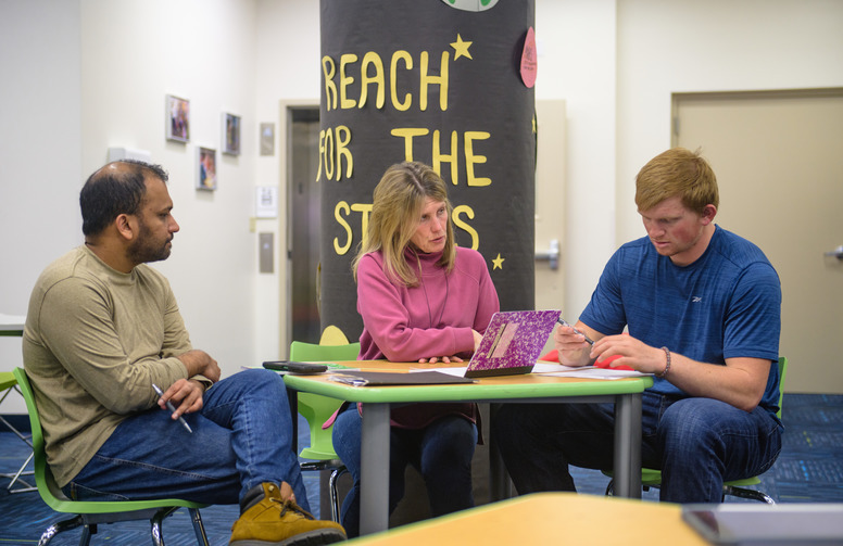 three people meet at the library