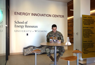 A UW student wearing a military uniform completes online coursework using a laptop computer.