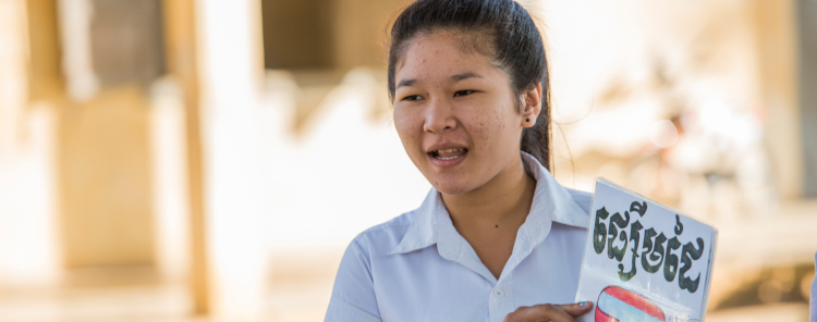 A student speaking and holding a book in Cambodia