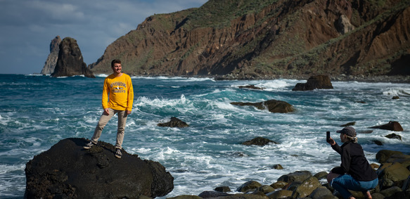 A student standing on large boulders in the ocean