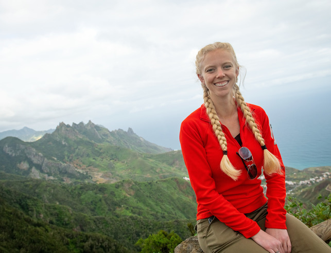 student smiles at a scenic outlook abroad