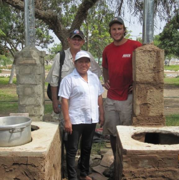 three men standing at newly installed cookstoves for a resturant in Peru