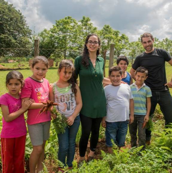 two pcvs standing with children in their school garden in Paraguay