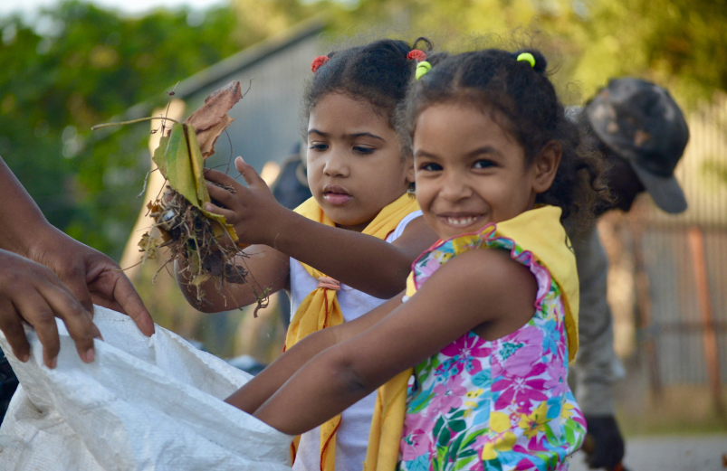 A girl gathering leaves and putting them in a bag