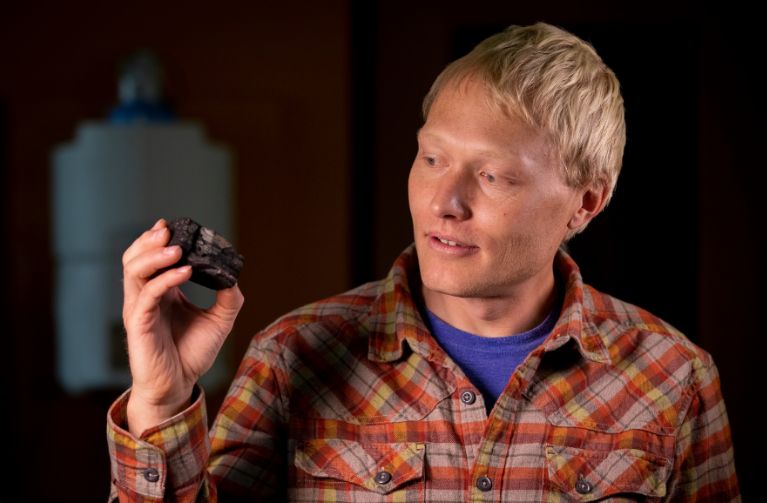 Picture of UW researcher holding a piece of coal.