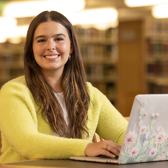 Student in library working at laptop