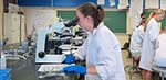 Female student looking into a microscope. 