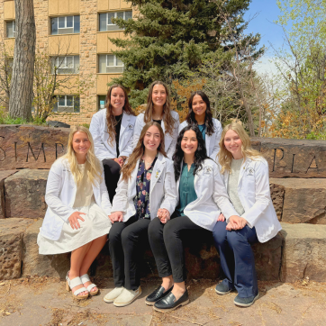 Students in white coats sitting