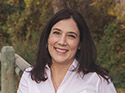 Woman in  white  top leaning on  a wooden fence