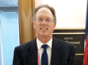 Man in suit  and tie standing outside of open door