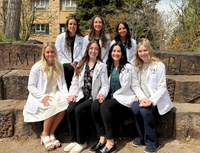 seven pharmacy students in white coats