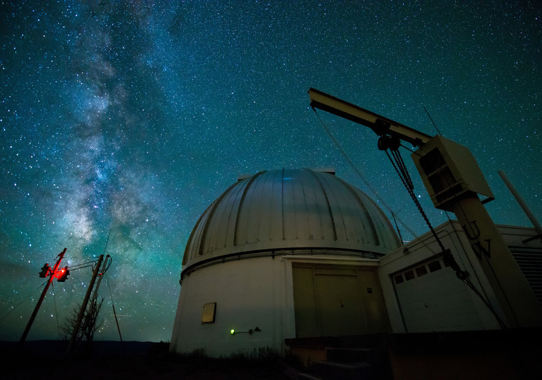 The Wyoming Infrared Observatory is shown in the forefront with the night sky in the background.