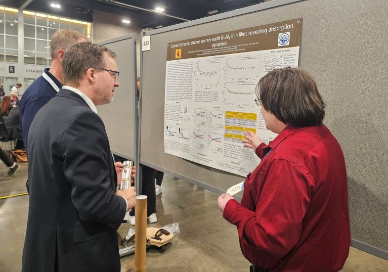 person explaining scientific poster on a wall to another