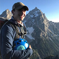 student in mountaineering gear stands on mountain