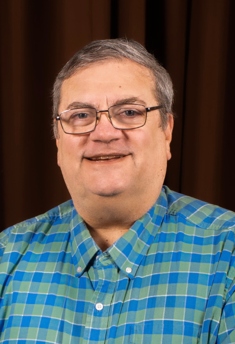 Smiling man wearing blue and green plaid shirt and glasses